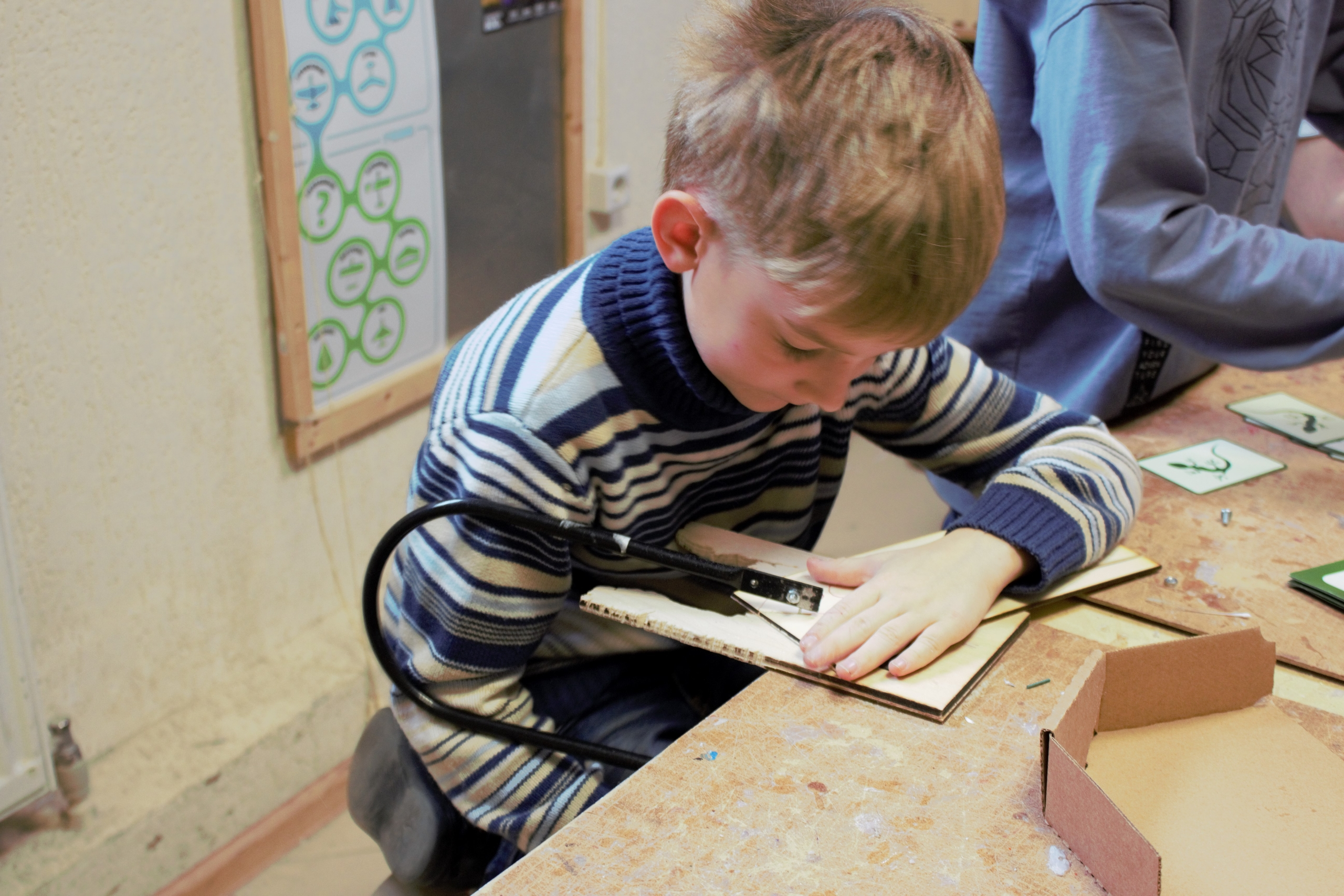 Ребёнок работает с деталями из фанеры